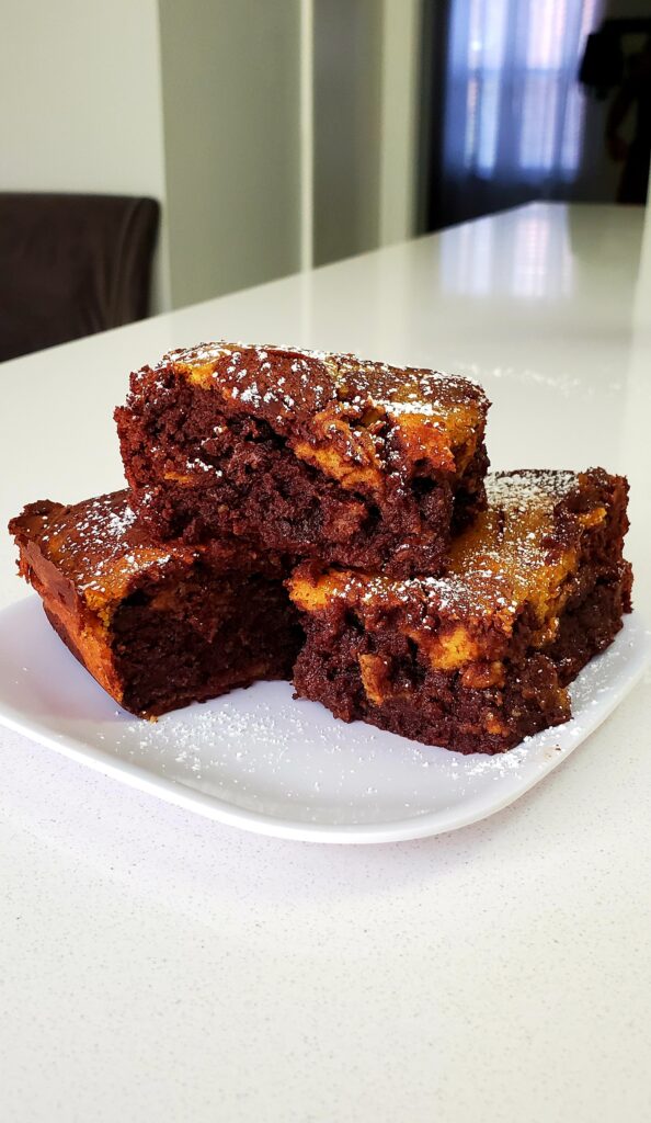pumpkin cheesecake brownies dusted with powdered sugar
